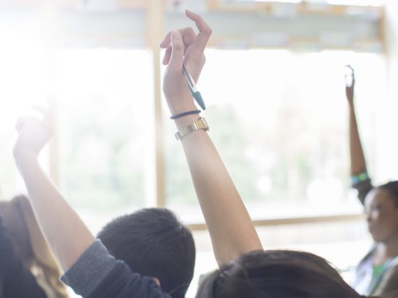 étudiants avec les bras levés dans la salle de classe